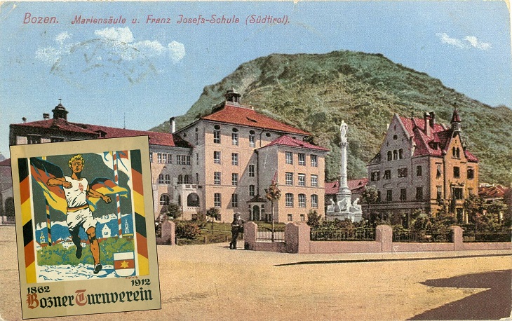 Plakat des Turnvereins vor dem Hintergrund der Schule und der Turnhalle