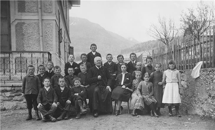 Volksschulklasse Niederolang: Die letzten Kinder, die noch unter Österreich geboren wurden mit Pfarrer Leopold Wallnöfer (Bildmitte) vor dem Gasthaus Steurer